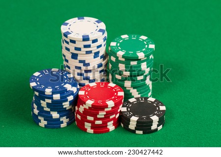 Stack of green, red, blue, white and black Playing Poker Chips in a green background