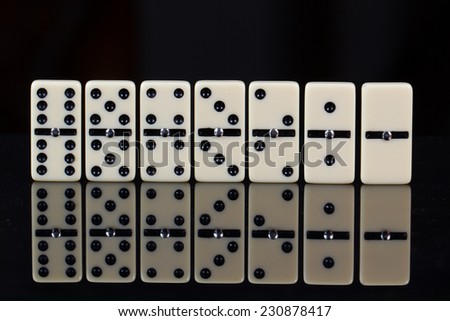 From six to zero Close up of domino pieces with black dots in reflective black background