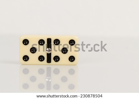 Five Close up of domino pieces with black dots in reflective white background