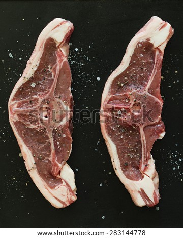 Raw lamb chops seasoned with salt and pepper.