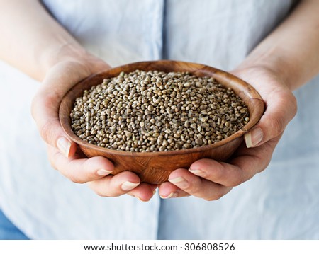 Organic Hemp Seeds. A woman holding a wooden bowl of hemp seeds.