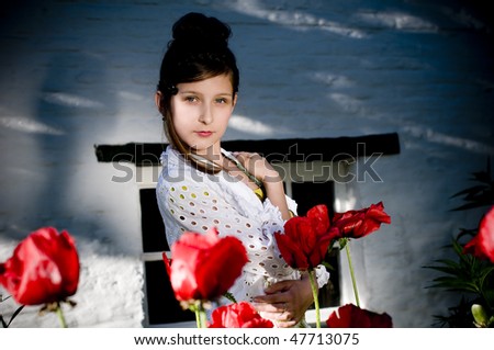 Teenage fashion girl showing off clothes and jewelry surrounded by huge red poppies