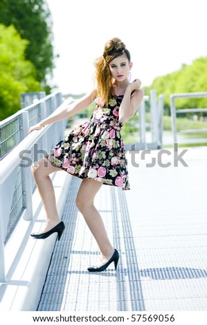Teenager girl model presenting clothes in the park near the water and a bridge