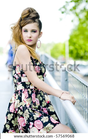 Teenager girl model presenting clothes on a bridge in the parc, light natural background