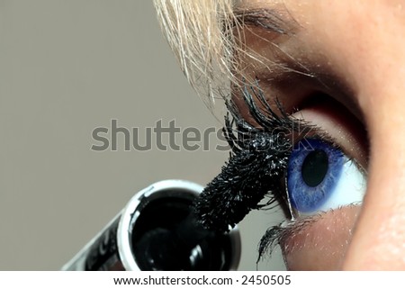 Beautiful blonde woman putting the mascara on her eyelashes