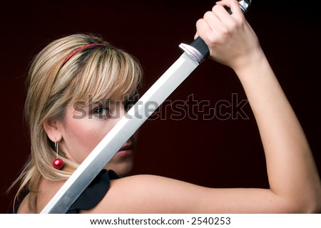 Beautiful woman holding japanese sword in front of her face