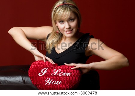 Beautiful blondie girl holding heart-shaped pillow I Love You