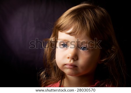 Portrait of beautiful little girl with blue eyes and curly hair on dark blue background. Focus on girl\'s right eye.