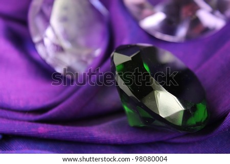 Green emerald gem stone on purple cloth