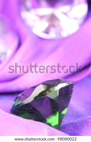 Green emerald gem stone on purple cloth