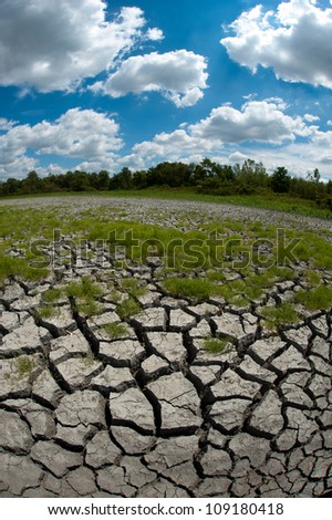Dried cracked bed of wetland during an extended drought in the midwest United States with blue sky