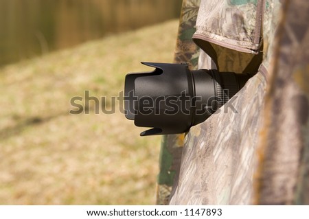 Telephoto lens protruding from photo blind erected for wildlife photography