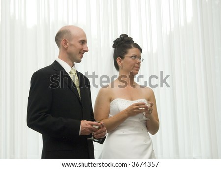 A bride and groom listen to the best man deliver the toast