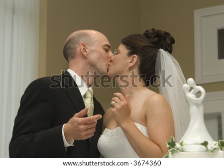 A bride and groom share a kiss after cutting the cake at their wedding reception