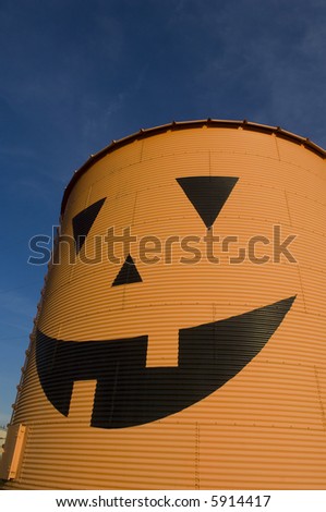A pumpkin face is painted on a grain bin