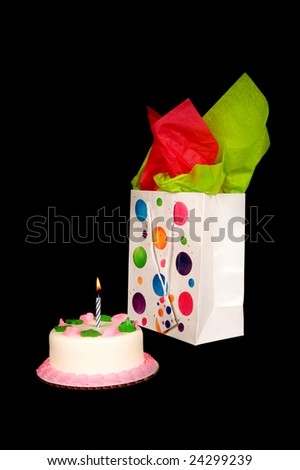 A small birthday cake and present on a black background