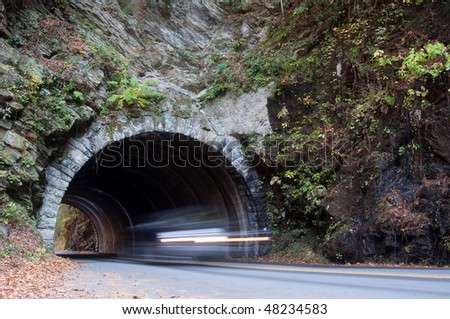 Vehicle drives through a tunnel through the mountains of Tennessee. Motion blur in car.