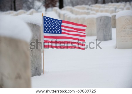 United States flag at the grave stone of a US solider in Jefferson Barracks National Cemetery near St. Louis Missouri. Photos taken after a winter storm.