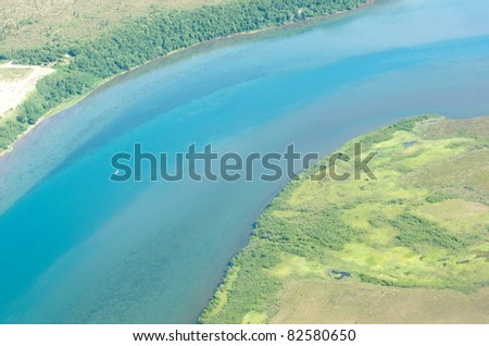 A small boat moves along a blue river in Alaska.