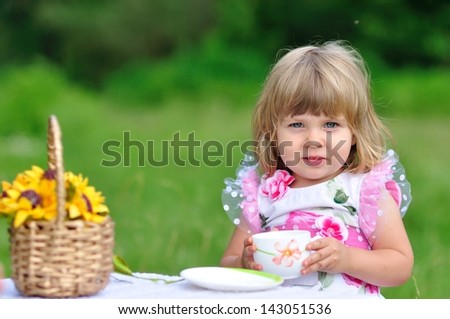 beautiful little girl drinking tea in nature