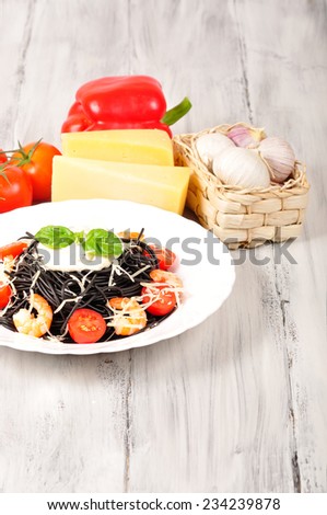 pasta made with cuttlefish ink with tomatoes and shrimp on the table with ingredients around