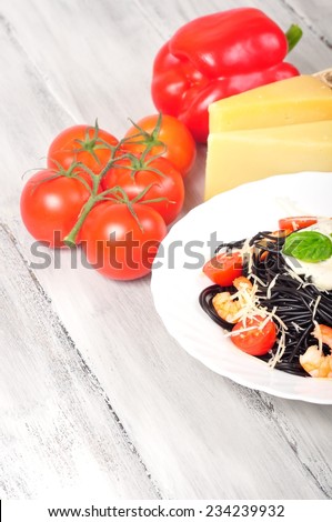 pasta made with cuttlefish ink with tomatoes and shrimp on the table with ingredients around