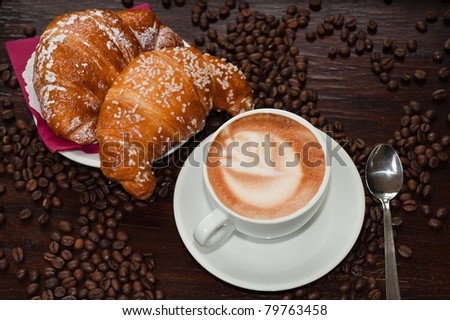 Cappuccino and croissant with coffee beans