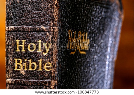 Old and damaged antique holy bible sacred religious book spine detail close up with vintage embossed gold lettering on worn binding