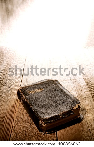 Old antique and damaged Holy Bible sacred Christian religious book in bright heavenly divine light on aged wood pulpit in a Protestant church