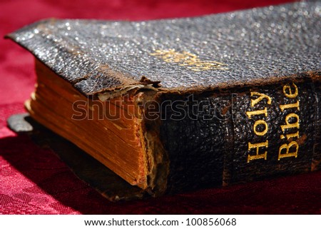 Old and damaged Holy Bible antique religious book gold leaf engraved spine title with fragile torn ancient cover on altar red fabric during a ceremony service in a protestant religion church