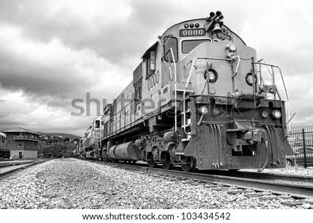 Diesel electric freight engine locomotives marshaled in tandem pulling a cargo train riding on a rail track in a railway depot railroad yard