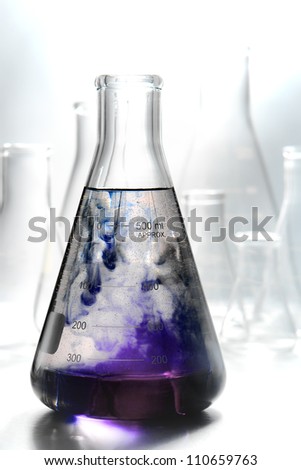Scientific laboratory glass conical Erlenmeyer flask filled with swirling and reacting purple chemical liquid mix in a reaction for a chemistry experiment in a science research lab
