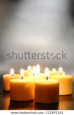 Votive candles burning with a soft glow flame with smoke above for meditation or relaxation in peaceful mood and soft ambiance