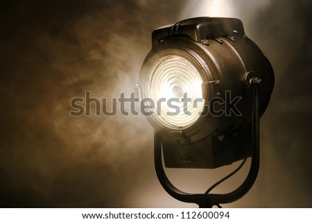 Hollywood old movie studio vintage Fresnel style halogen hot spot light in smoke in sepia