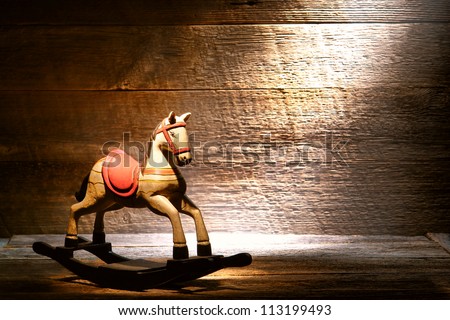 Nostalgic Americana scene of an antique reproduction wood toy rocking horse on aged wooden plank floor in a dusty old house attic lit by soft diffused sunlight through a window