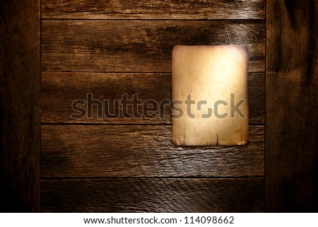 Old blank parchment paper western poster board notice with empty copy space display on aged and weathered barn wood wall background in grunge light