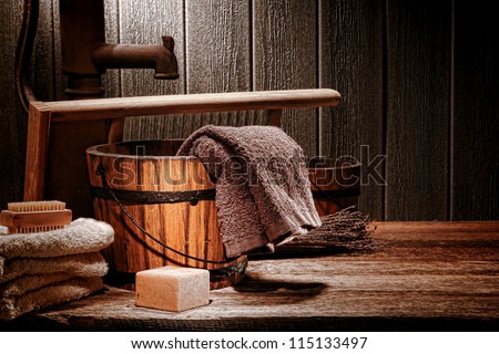 Antique laundry manual wash scene with old towels and ancient natural soap bar near vintage wood bucket and washboard on an aged historic house wooden washing counter