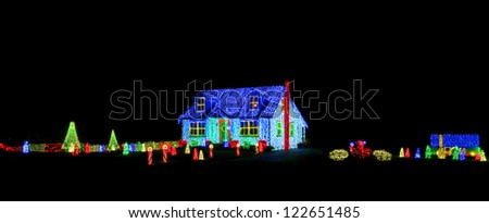 Intense bright colors LED Christmas light show and display on a house and its yard for festive holiday illuminations on a black night