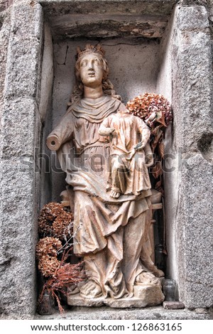 Antique stone statue of the blessed Virgin Marie holding the infant Jesus in a wall alcove of an old historic church