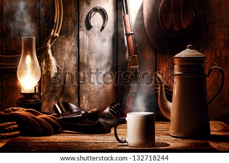 American West legend cup of hot steamy coffee and brewing pot on an old wood table with traditional cowboy gear and aged tools in an antique western wooden cabin on a ranch