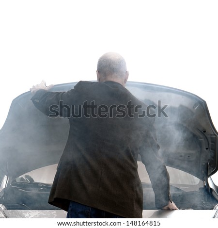 Auto driver standing in front of a broken down car open engine compartment hood with smoke from an automotive fire or hose leak steam waiting for emergency repair on a road