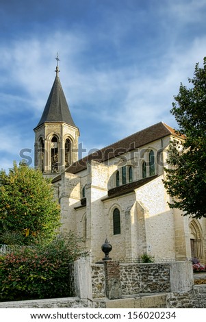 Traditional stone gothic catholic church place of worship building with pointy steeple and masonry walls in a small rural village in France