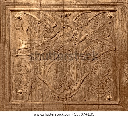 Ancient religious wood carving art depicting a king surrounded by angels carved on an antique wooden door at an antique French village church in France
