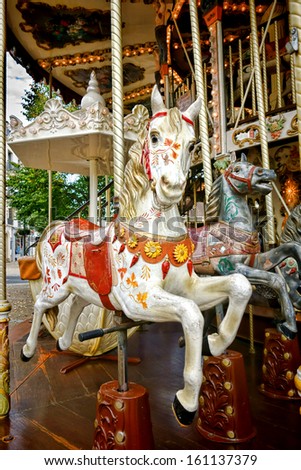 Vintage carved wood nostalgic carousel riding horse with antique painted decor mounted on a classic brass pole on an old amusement merry go round