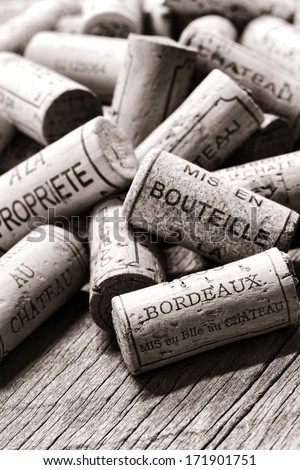 Wine corks from opened bottles with generic French winemaker wording naming local bottling at the castle or at the property in a loose pile on an old weathered vineyard cellar wood table in France