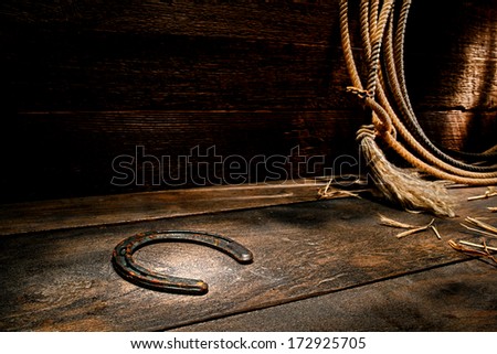 American West rodeo rusty old forgotten western horseshoe on ranch barn wood floor with lasso lariat on antique wooden wall