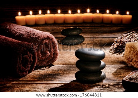 Black polished smooth hot massage stones in a Zen inspired cairn on a vintage wood boards table in a rustic natural and holistic spa for a traditional relaxation and health rejuvenation treatment