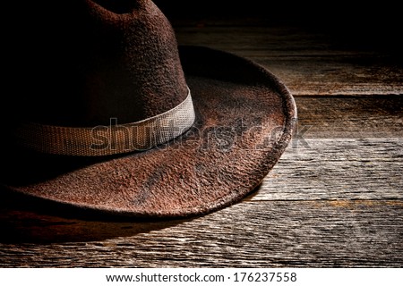 American west rodeo used and worn brown felt hat with old dirty fabric band on weathered wood planks in a western ranch wooden barn