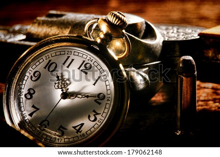 American West Legend outlaw antique pocket watch keeping time and leaning against a loaded bandit revolver gun with an assassin bullet ready for a gunslinger western frontier gunfight