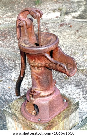 Antique style reproduction rusty manual water well pump device with hand crank